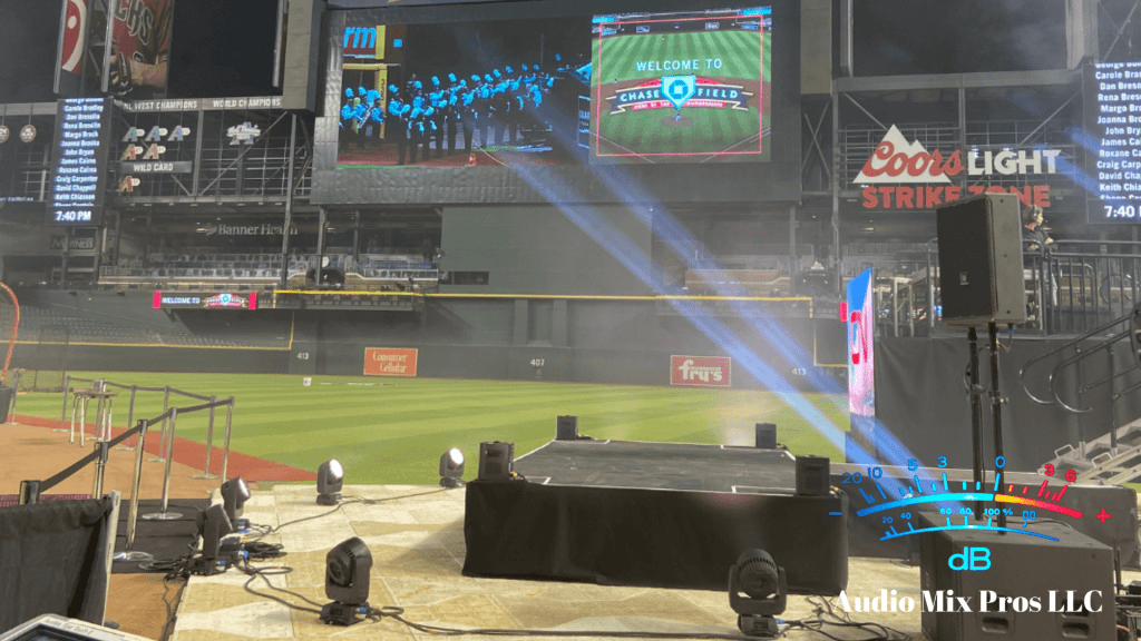 View of a stage setup at Chase Field for an event, featuring large screens displaying a welcome message and stage lighting equipment in the foreground.
